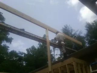 Carpenter setting a ridge beam over a new addition frame — Ice Dam Removal by Roofing Brothers in Flowood
