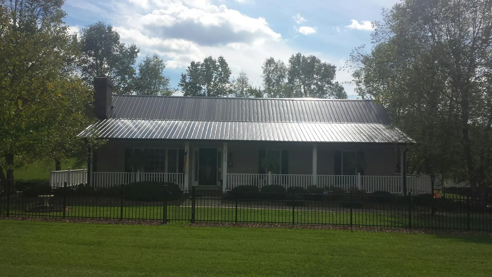 Gray metal roof on a brick ranch with a full width front porch — Gutter Guard Installation work by our crew in Flowood